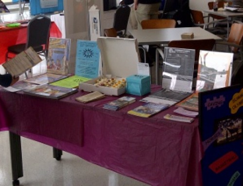 A woman reads a flier from the literature table at a March, ’13 corporate camp fair